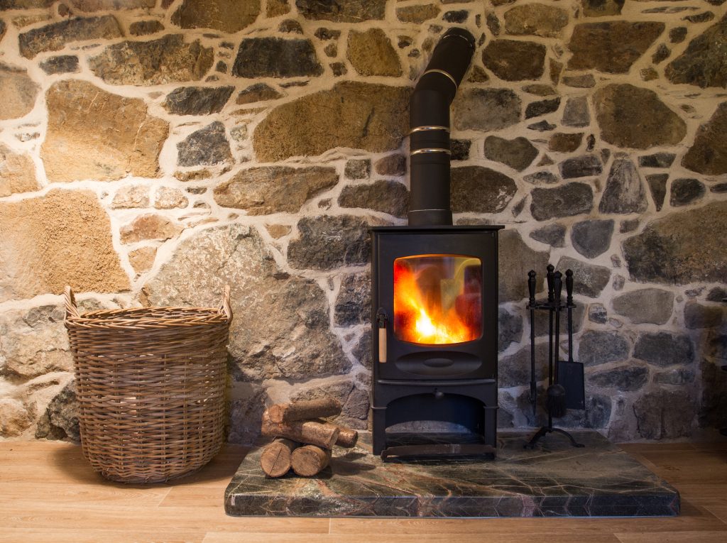 A wood burning stove fireplace in a cosy stone cottage with copy space